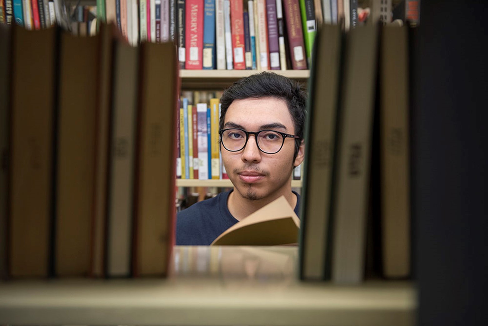 Student wearing glasses looking for library books